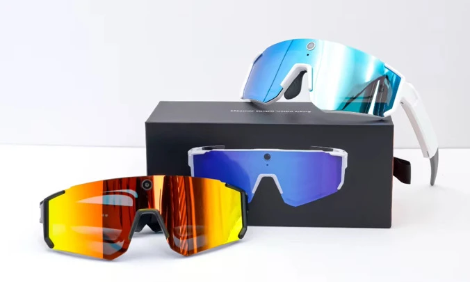 Gafas blancas con lente azul y negras con lente naranja junto a la caja
